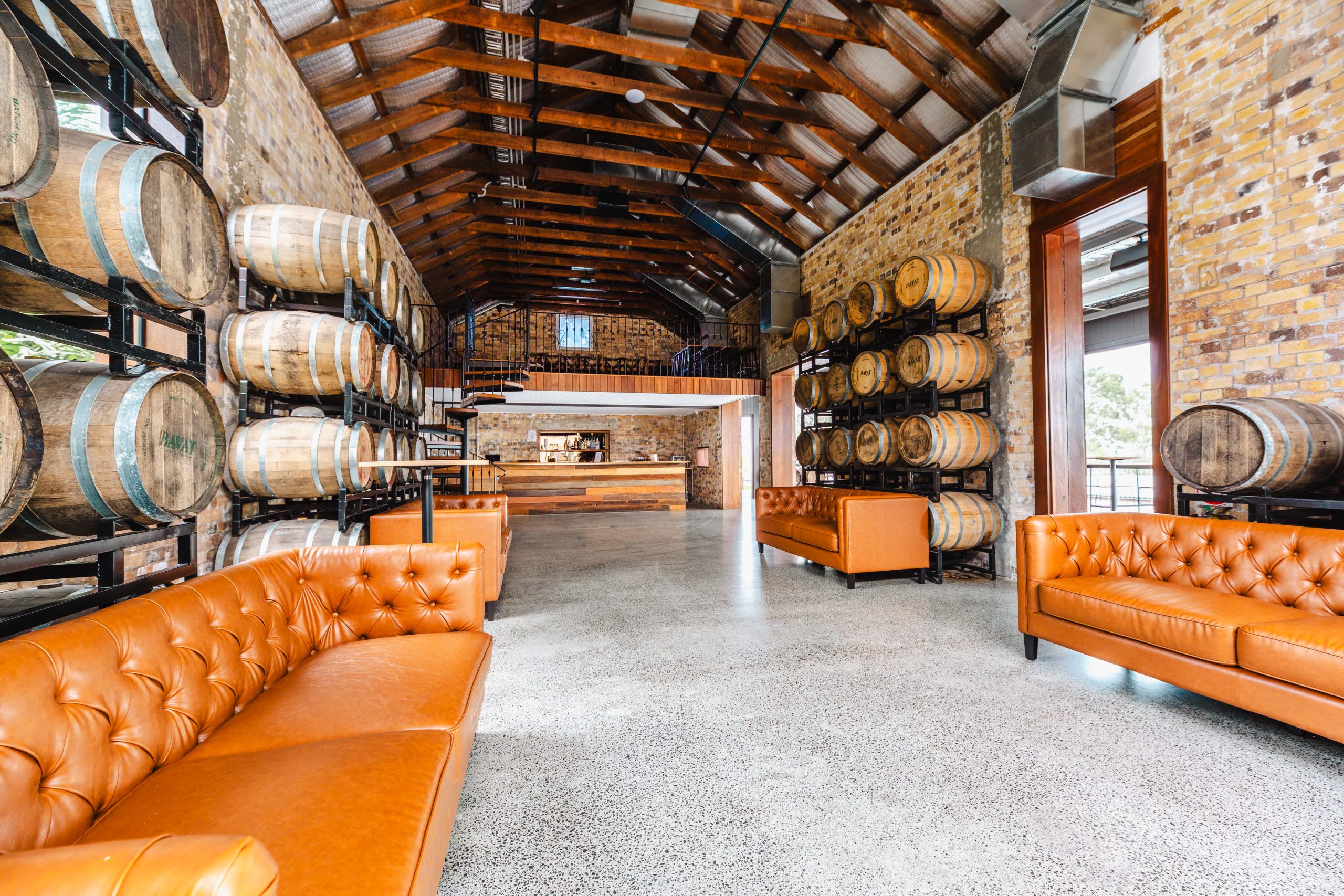 The interior of the Engineers Hut, with heritage brick walls, timber roof trusses and stacked barrels.